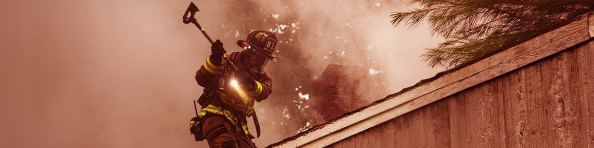 Firefighter scaling a roof swinging an axe
